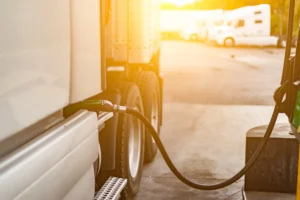 close up of a semi truck filling gas at the pump with the sun coming up in the background
